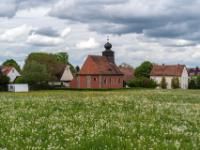 Löwenzahnwiese vor der Bubenreuther Kirche unter dramatischem Himmel - Franken